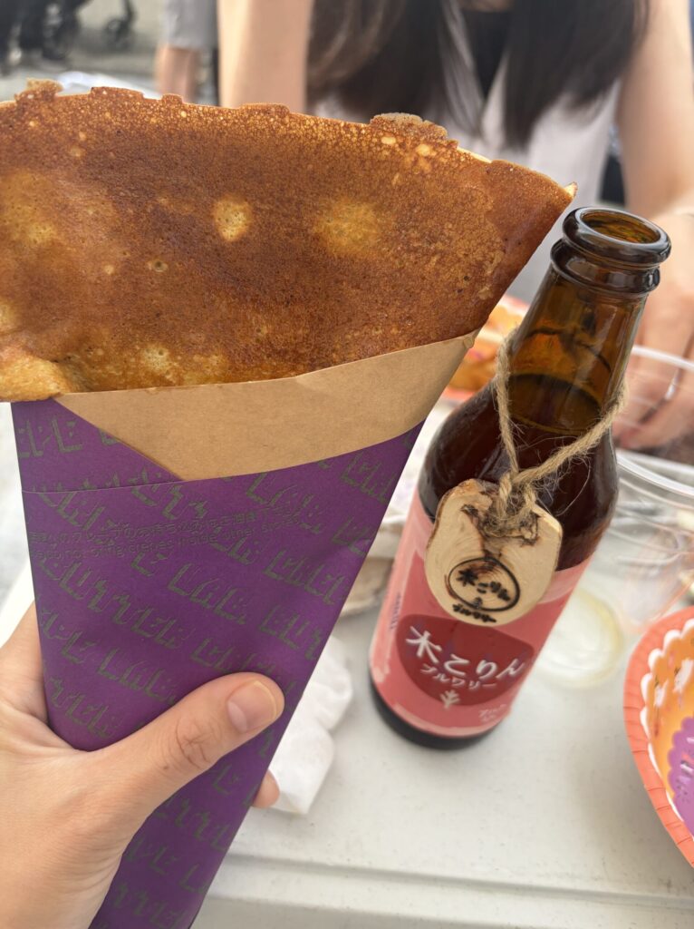 紫の紙に包まれたクレープと木こりんブルワリーの瓶ビール