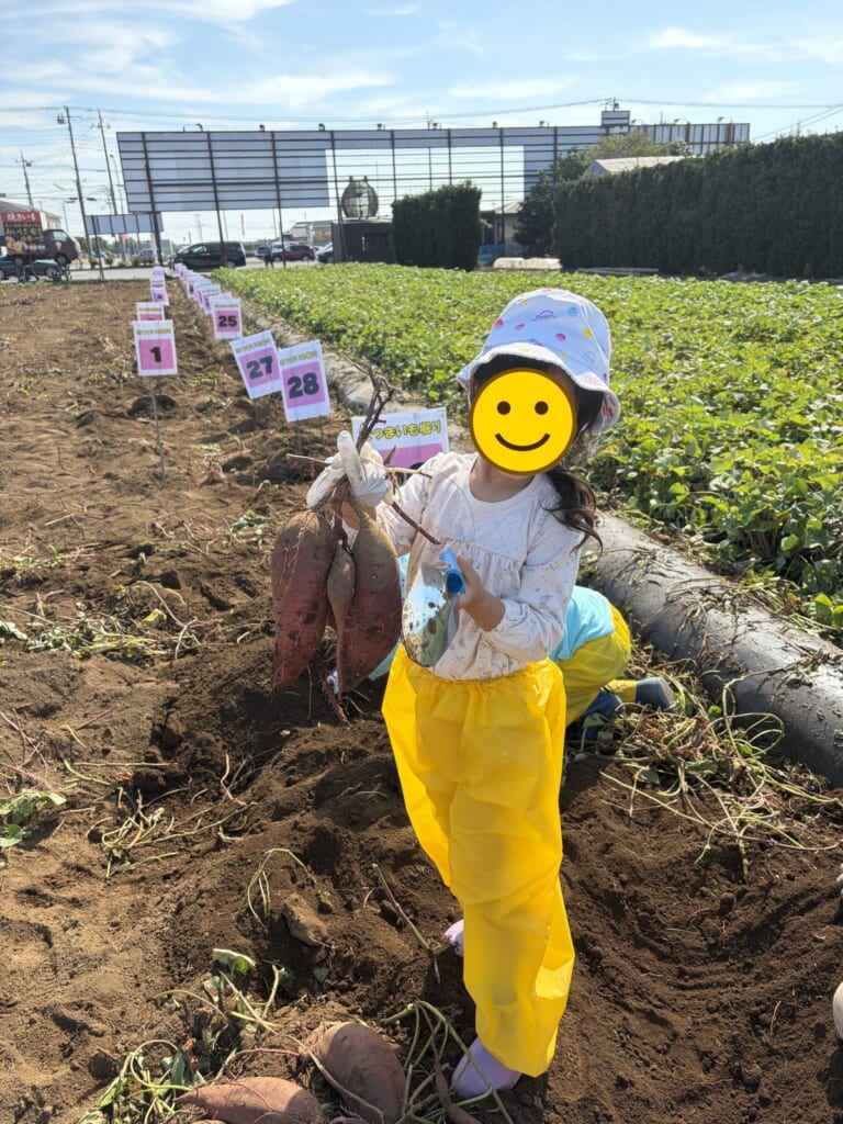 成田ファームランドで掘ったさつまいもを持つ娘